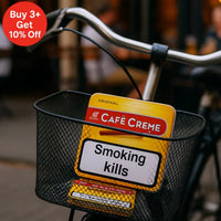 Bicycle basket with Cafe Creme originla cigar pack and 'Smoking kills' sign, blurred background | Vape Dokha UAE