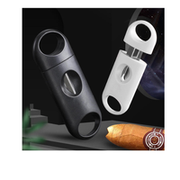Black and white cigar cutters with a cigar on a dark background. Vape Dokha UAE