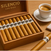 Box of Silencio Los Rios cigars with a cup of coffee and newspaper on a wooden table. Vape Dokha UAE