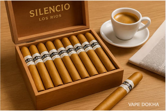 Box of Silencio Los Rios cigars with a cup of coffee and newspaper on a wooden table. Vape Dokha UAE