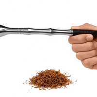 Hand holding a steel medwakh pipe over a pile of tobacco leaves on a white background. vape dokah UAE