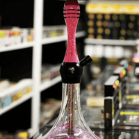 Pink and black hookah with a blurred store shelf in the background. Vape Dokha UAE