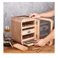 Wooden humidor with glass door on a wooden table, with a glass of wine and a lighter in the background. Vape Dokha UAE