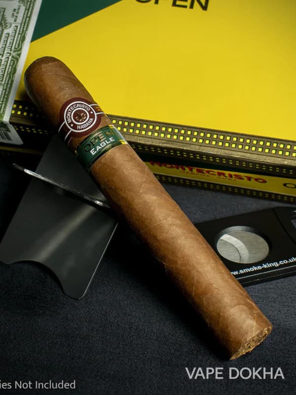 montecristio Cigar with a branded band, cutter, and money in the background on a dark surface. Vape dokha UAE